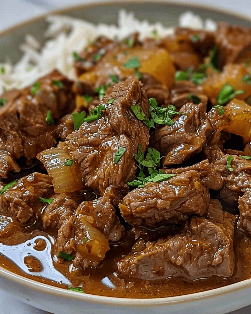 A close-up of Simple Beef Mechado served with a rich, flavorful sauce and garnished with fresh parsley on a bed of steamed rice.