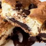 Gooey Chocolate Chip Cheesecake Bars with layers of creamy cheesecake, rich chocolate ganache, and a golden, flaky cookie topping.
