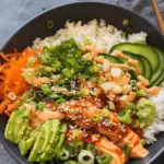 Spicy salmon bowl with glazed salmon, jasmine rice, avocado, cucumber, shredded carrots, green onions, peanuts, sesame seeds, and spicy mayo drizzle.