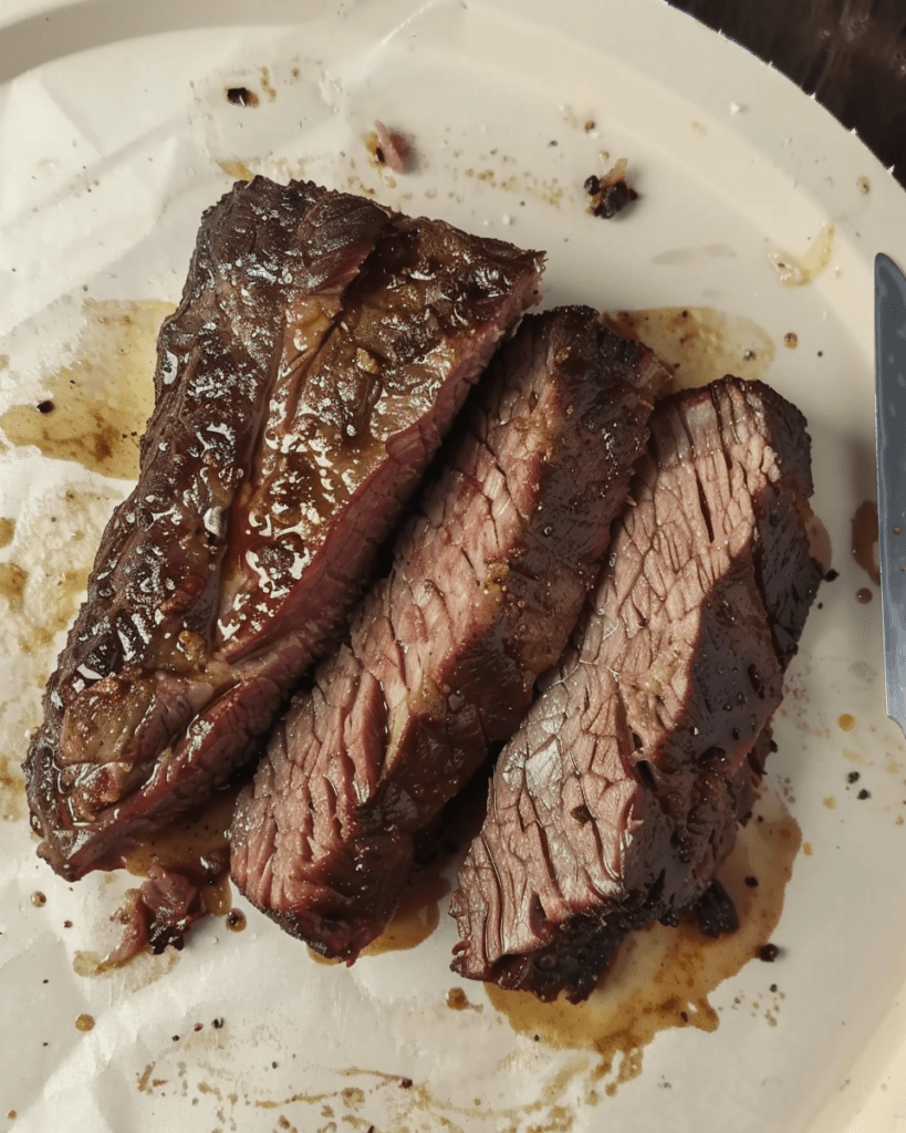 Slow-cooked Texas-style boneless beef ribs, sliced and served on a plate with juices and seasoning.