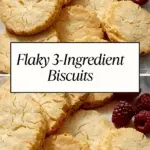 Golden, flaky 3-ingredient biscuits with cracked tops arranged on parchment paper, garnished with fresh raspberries.