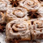 Freshly baked chai cinnamon rolls topped with vanilla glaze and garnished with whole star anise.