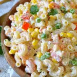 Bowl of creamy Mexican macaroni salad with elbow pasta, corn, peas, carrots, and bell peppers in a creamy dressing.