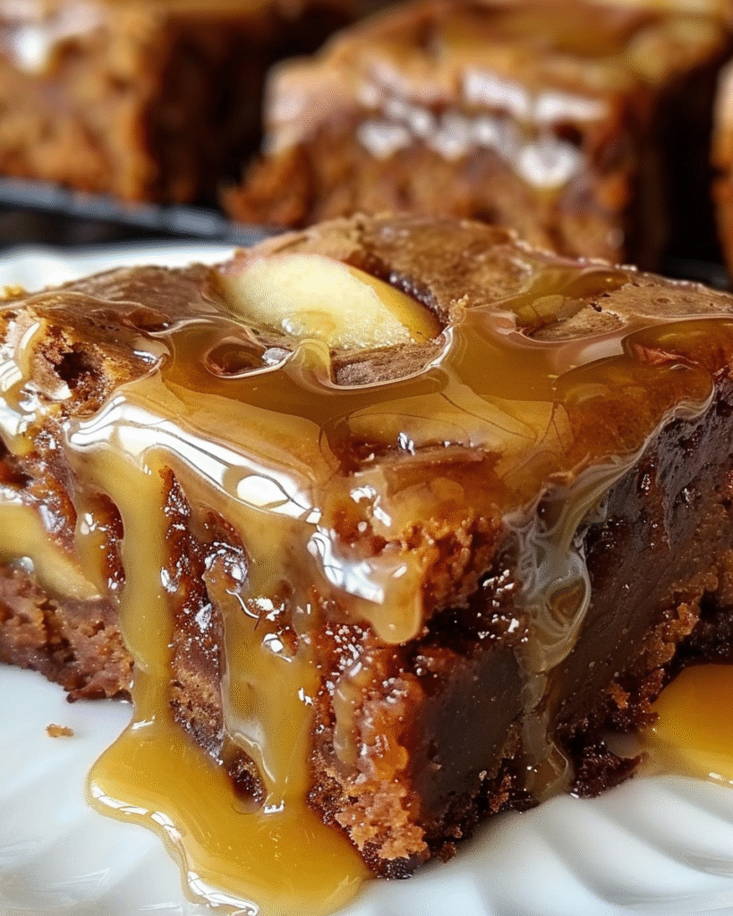 Close-up of a rich apple brownie square topped with caramel sauce and baked apple slices.